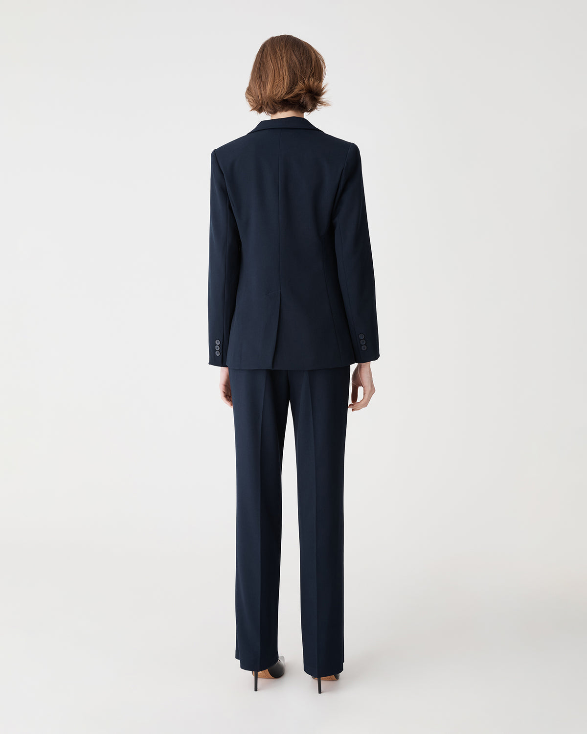Back view of the navy blazer showing the back vent, worn with matching pants