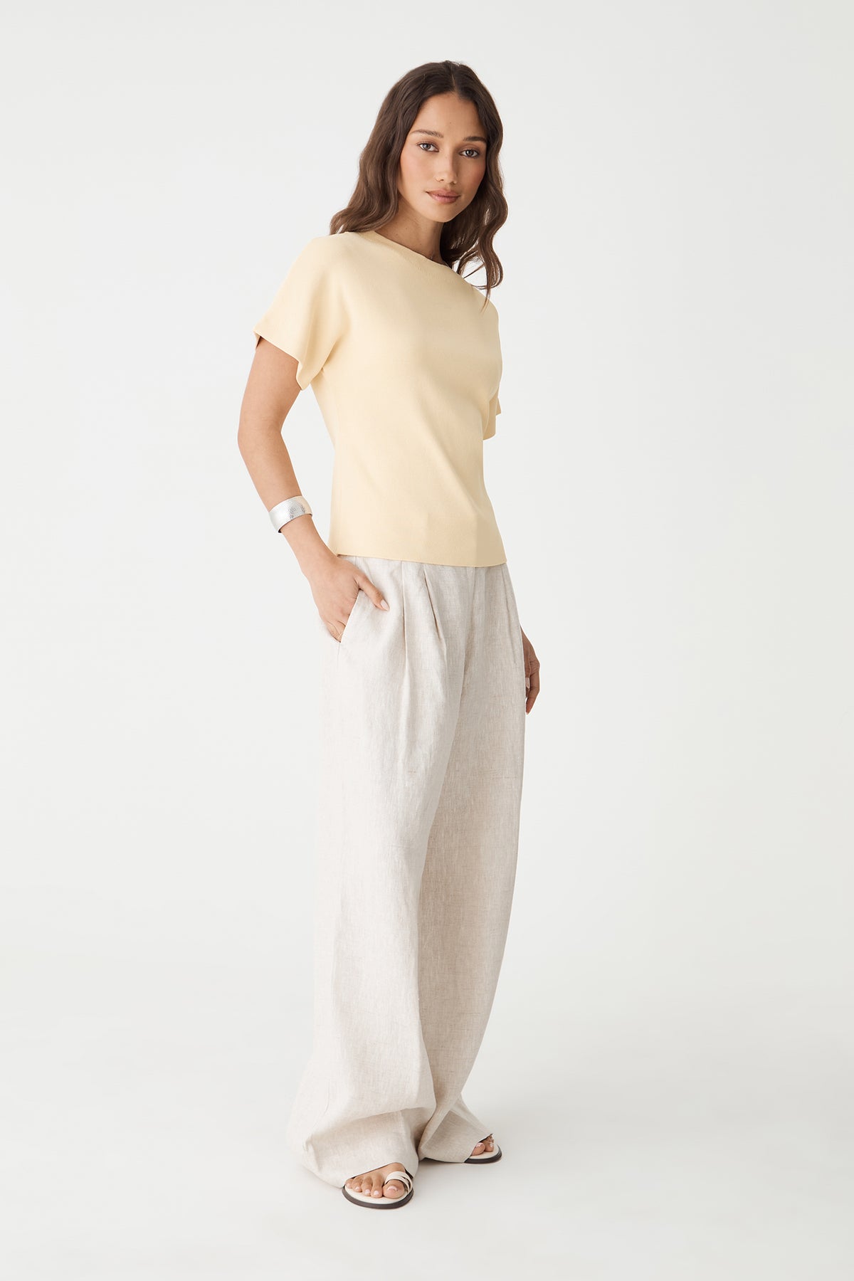 Side view of the butter yellow Jemma Relaxed Knit Top with cream trousers