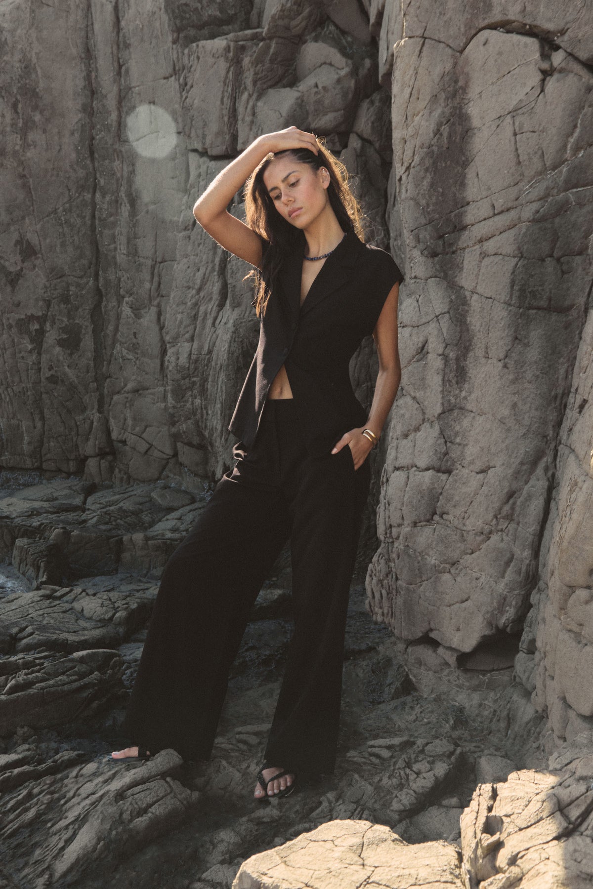 Milton Wide Leg Pants in black worn outdoors against rocks, full-length side view