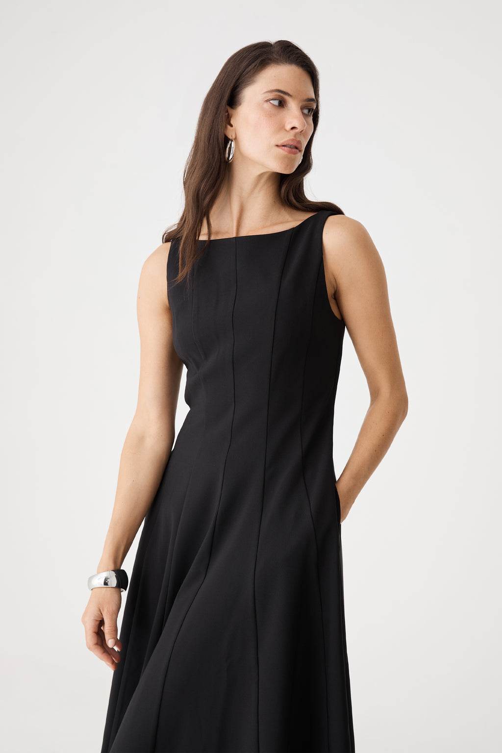 Close-up of the black dress bodice showing vertical panel seams and boat neckline