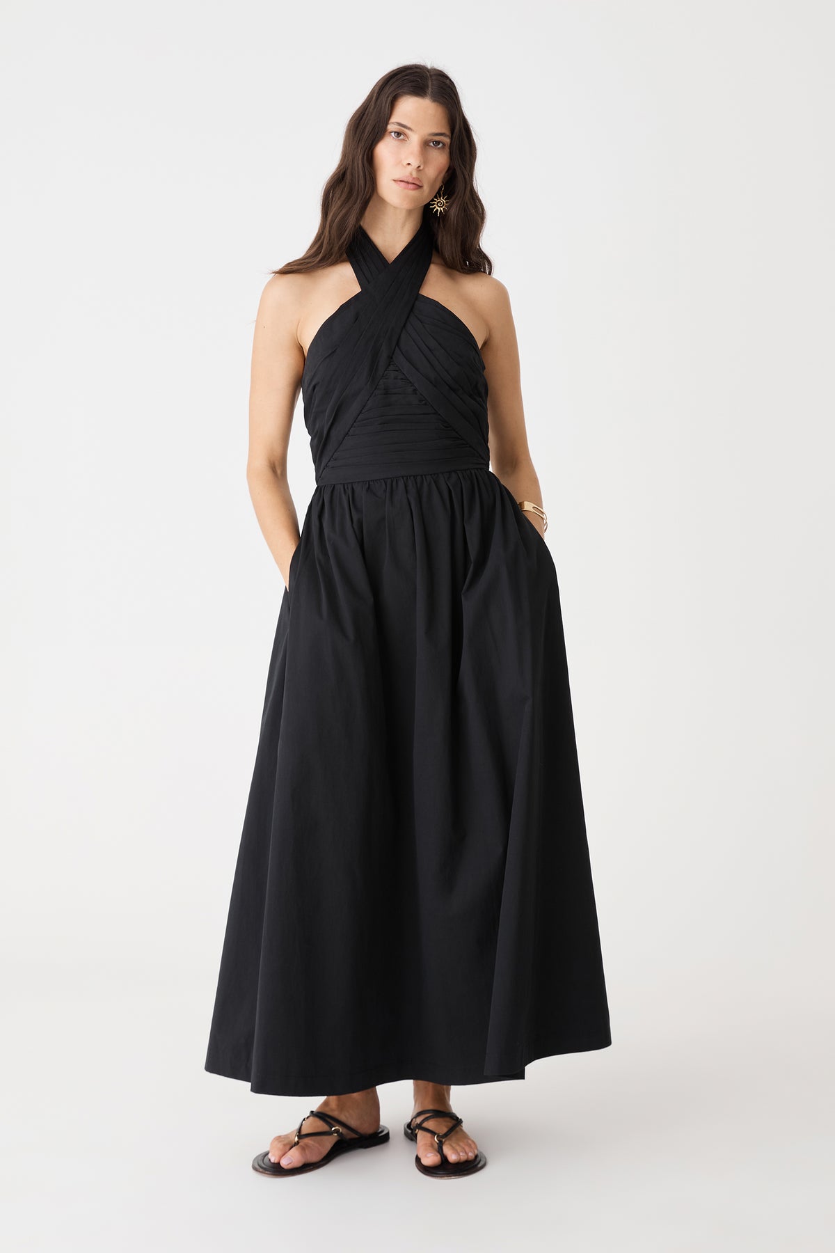 Front view with hands in the in-seam side pockets of the black Kayleigh Cotton Halter Dress