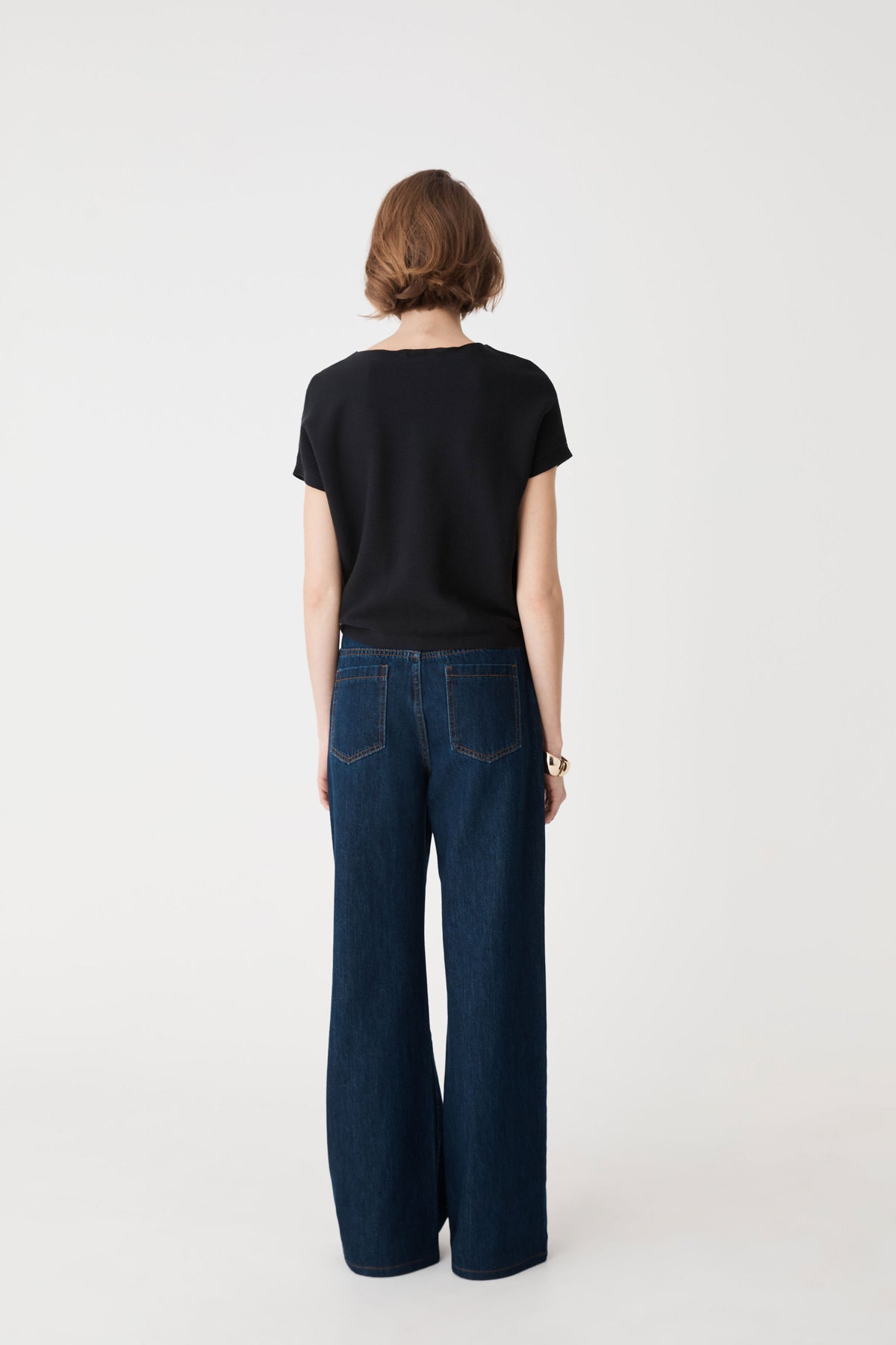 Back view of the black knit top with dark blue wide-leg jeans