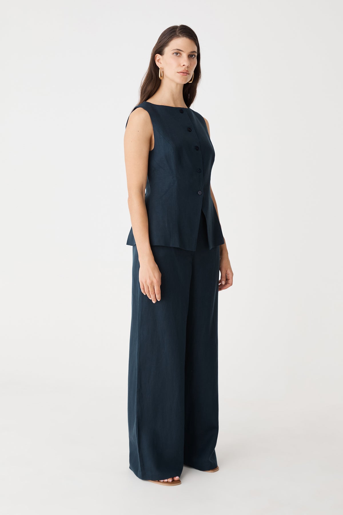 Side view of the navy Phoebe vest top with flared hem over matching pants