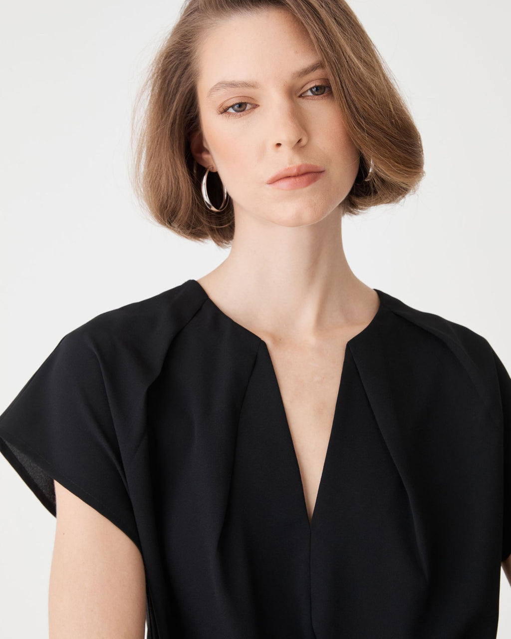 Close-up of the split V-neckline and shoulder pleating on the black top