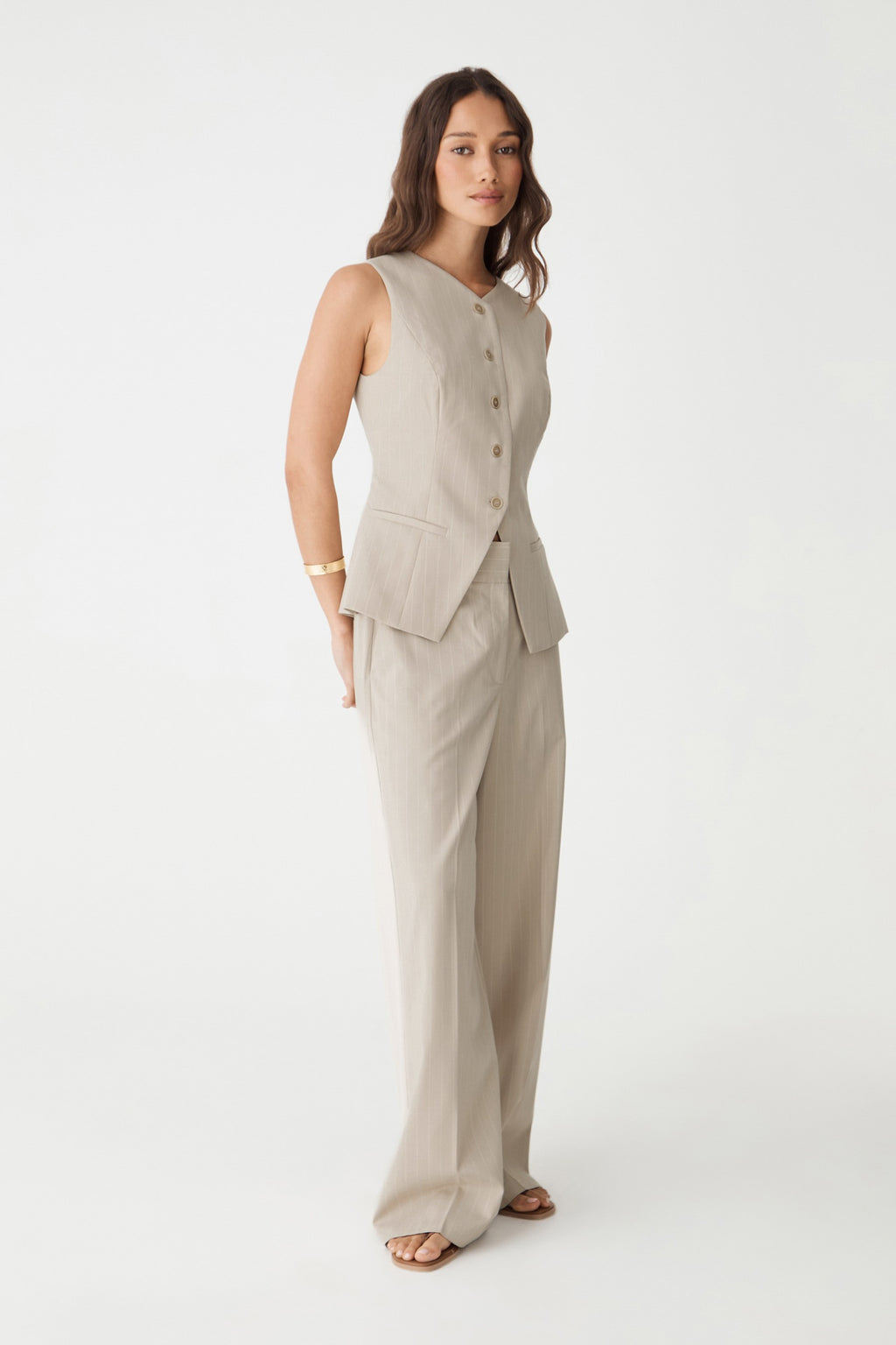 Side view of the beige pinstripe wide leg pants worn with the matching buttoned vest