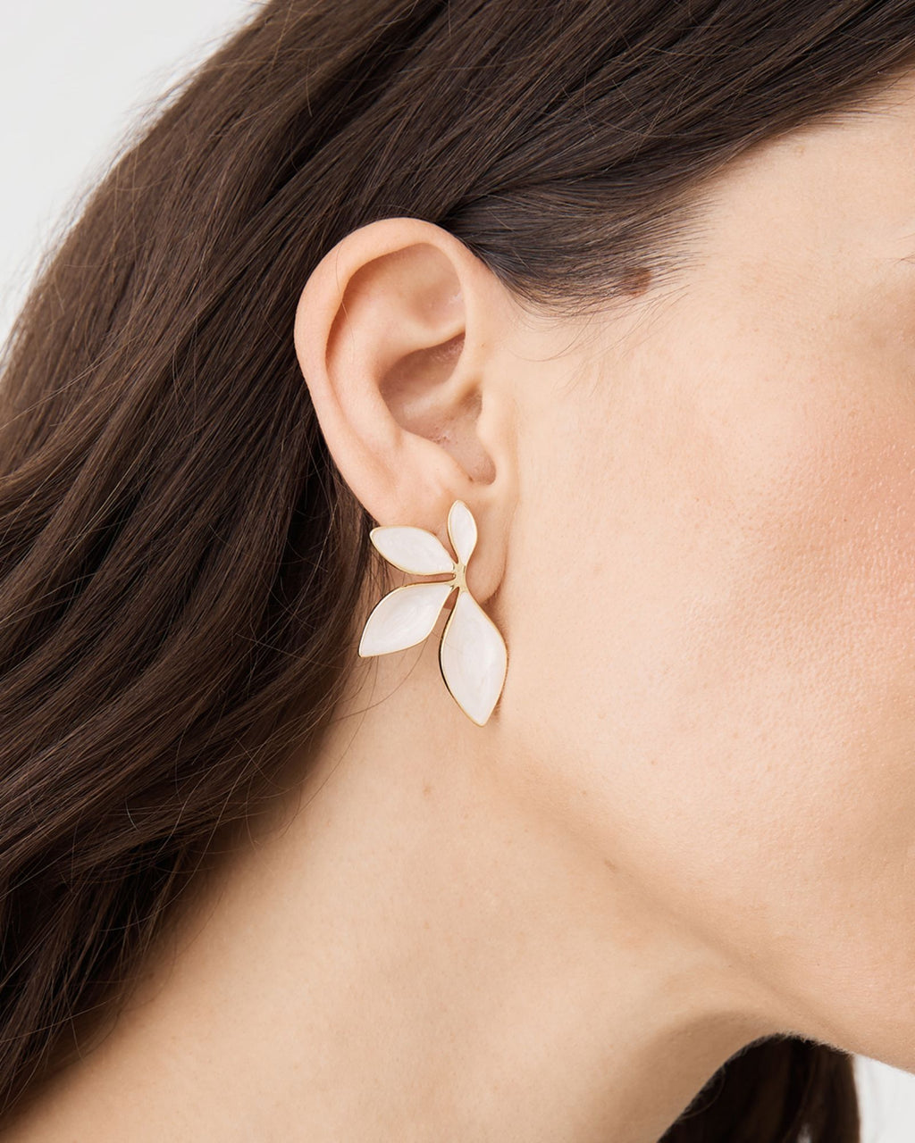 Close-up side view of the ivory four-petal earring on the ear