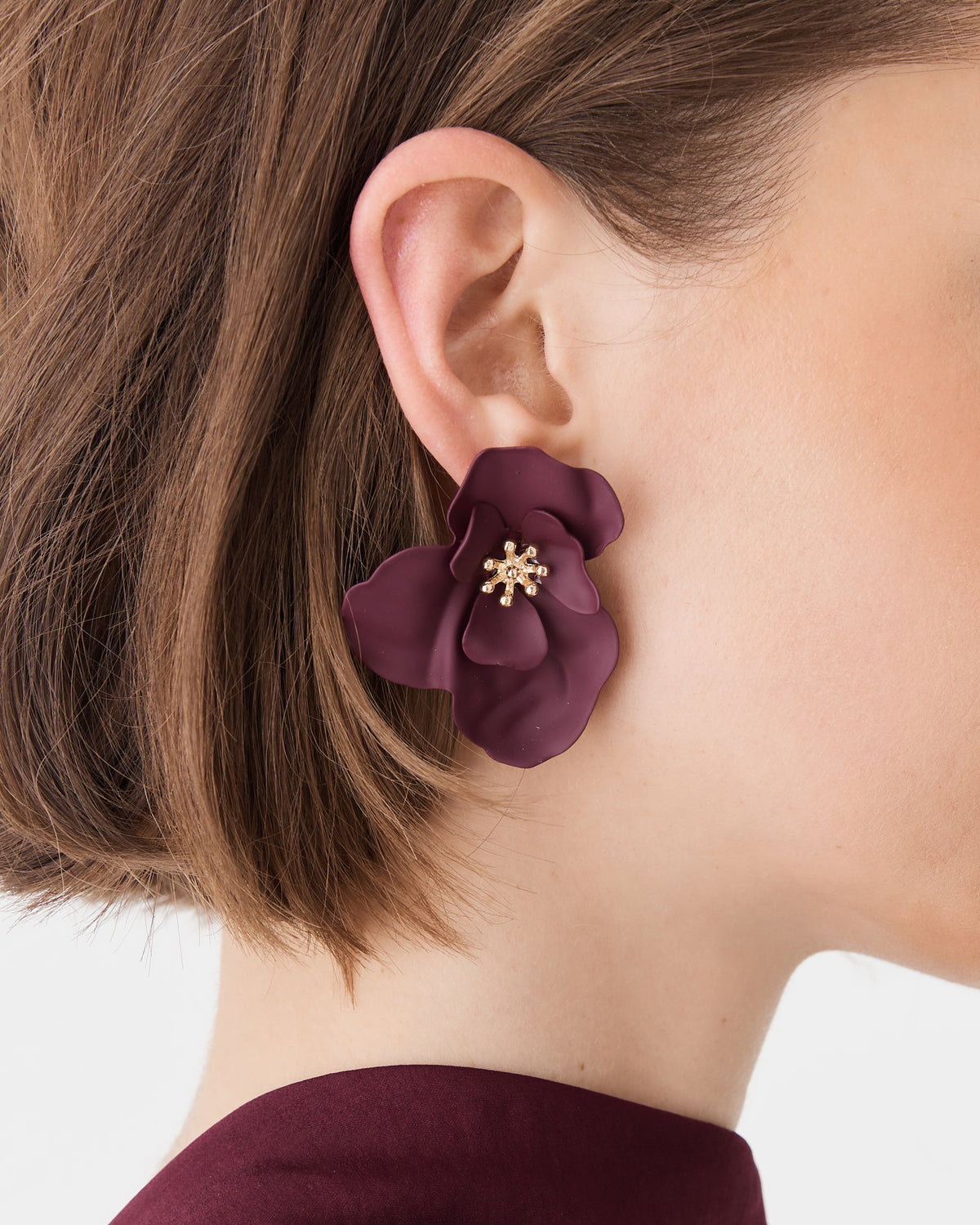 Amara Bloom Earrings in burgundy, close-up of layered floral stud worn on ear with gold-tone centre