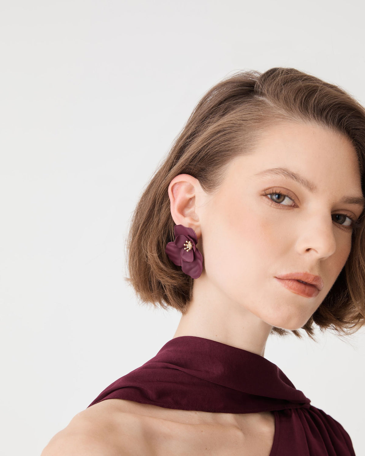 Amara Bloom Earrings in amaranth worn with burgundy top, three-quarter view of layered petals