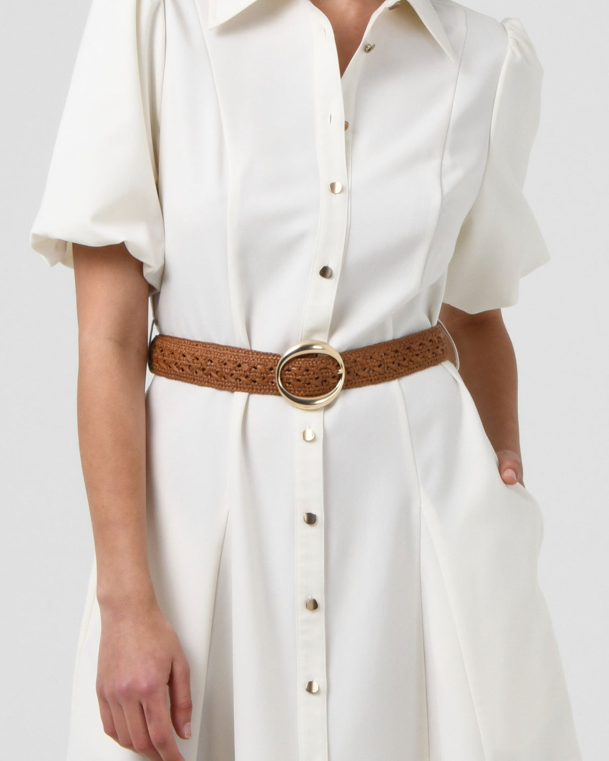 Close-up of the tan crochet belt with round gold-tone buckle at the waist