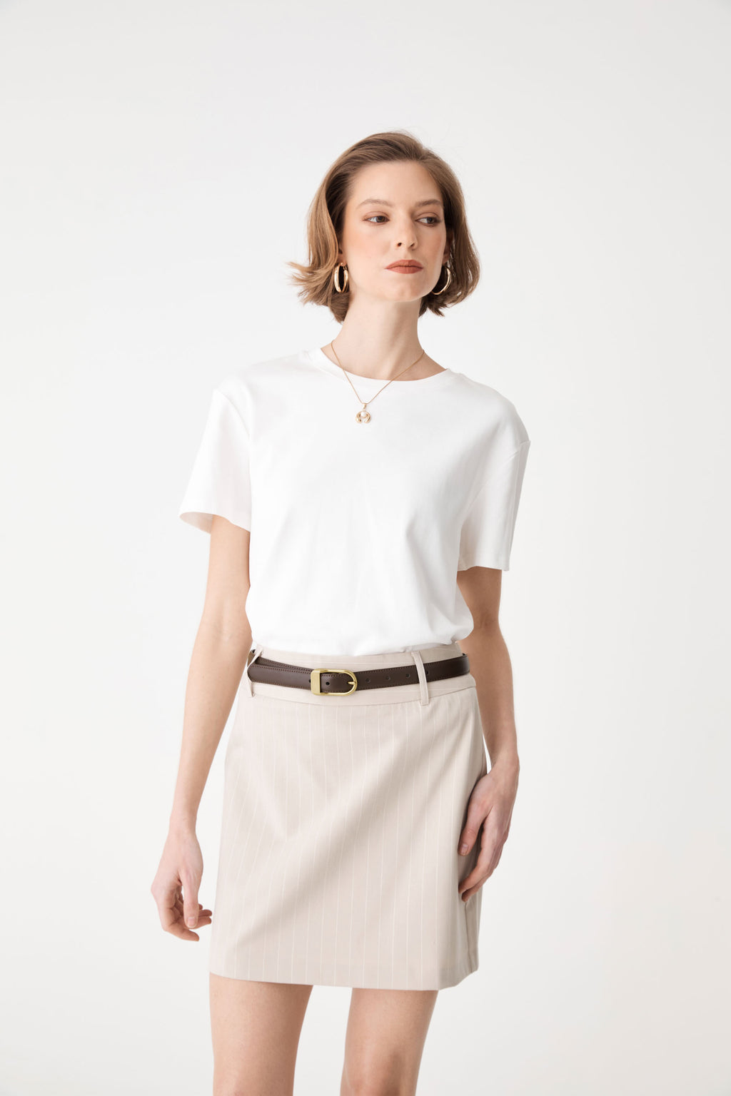 Front view of the dark brown belt worn over a cream skirt with a white tee