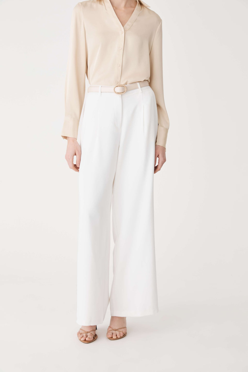 Full-length front view of the cream Aura Leather Belt worn with white trousers and beige shirt